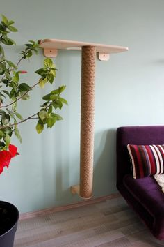 a cat tree in the corner of a room with a couch and potted plant