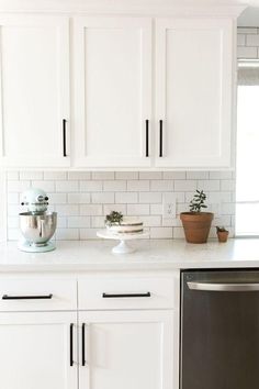 a kitchen with white cabinets and stainless steel dishwasher on the counter top in front of an oven