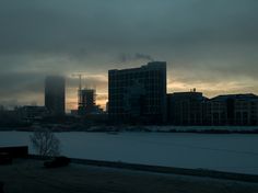 the sun is setting behind some buildings on a cloudy day with no one in sight