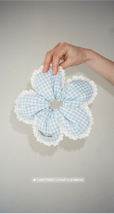 a hand holding a blue and white gingham flower