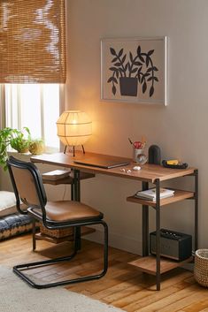 a room with a desk, chair and lamp next to a window that has blinds on the windowsill