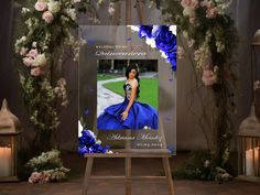 an easel with a blue dress and flowers on it in front of a backdrop