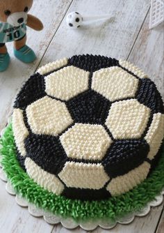 a cake with a soccer ball on it next to a teddy bear and other decorations