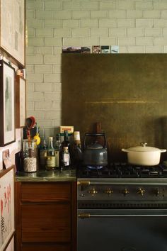 a stove top oven sitting inside of a kitchen next to a wall with pictures on it