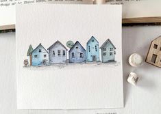 a watercolor painting of houses on paper next to a rubber stamp and some stamps