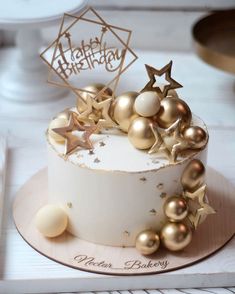 a white cake with gold stars and decorations on it's top, sitting on a plate