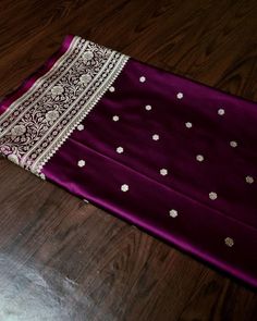 a purple and white dress laying on top of a wooden floor next to a table