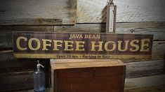 a coffee house sign hanging from the side of a wooden wall next to a box