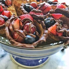 chocolate waffles with strawberries and blueberries on top are served in a bowl