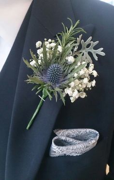 a boutonniere with white flowers and greenery on it's lapel