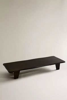 a black table sitting on top of a white floor in front of a gray wall