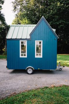 a tiny blue house sitting on top of a gravel road