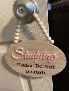 a sign that says studying please don't disturb on the door handle with beads hanging from it