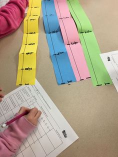 two children are cutting out strips of paper with scissors on the table next to each other