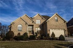 a large brick house with two garages in the front yard and landscaping around it