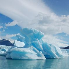 an iceberg floating in the water near mountains