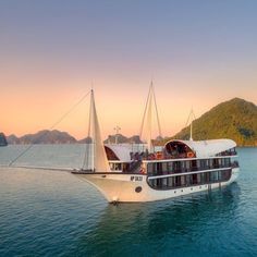 a large white boat floating on top of the ocean next to a small mountain range