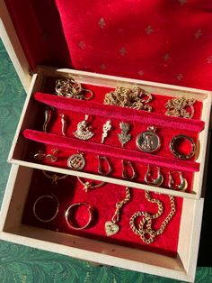 an open box containing various rings and necklaces on a red cloth covered tablecloth