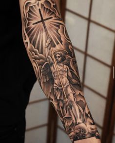 a man with a cross and angel tattoo on his arm