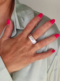 a woman's hand wearing a ring with a diamond on it