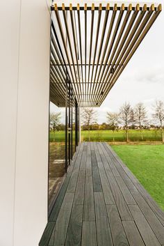 an outdoor deck with wooden slats and green grass in the backgrouds