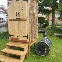 a wooden outhouse sitting on top of green grass