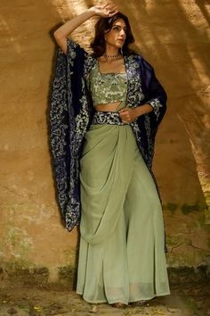 Navy blue cape with resham, sequin, floral embroidery. Paired with green sharara, attached draped dupatta, bustier and belt.
Component: 4
Pattern: Embroidery
Type Of Work: Resham, floral, sequin, floral
Neckline: Jacket: Open, Bustier: Square
Sleeve Type: Cape: Flared sleeves, Bustier: Sleeveless
Fabric: Organza, georgette
Color: Blue,Green
Other Details: 
Cutwork border hem
Occasion: Sangeet - Aza Fashions Green Sharara, Organza Jacket, Embroidered Cape, Organza Embroidery, Blue Cape, Blue Organza, Party Wear Indian Dresses, Sharara Set, Pattern Embroidery