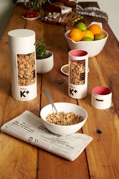 a table topped with bowls of cereal and oranges next to cups filled with oatmeal