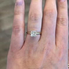 a woman's hand with a diamond ring on top of her finger, and the other hand holding an engagement ring