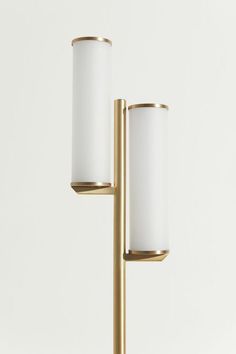 two brass candlesticks with white glass shades on each candle holder and one light is gold