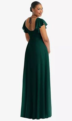 a woman in a long green dress is looking back at the camera and she has her hands on her hips