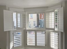 an empty room with white shutters on the windows