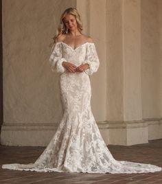 Introducing the Aspen Dress—your one-of-a-kind wedding gown brought to life. This off-the-shoulder wedding dress with sleeves is designed to make you feel like the most unique and beautiful bride. Crafted from luxurious textured cord cotton lace, it combines comfort with elegance. The off-the-shoulder neckline and dipped lower back create a stunning silhouette, while the voluminous puffed sleeves add a touch of romance.

The trumpet-fitted silhouette features a princess seaming down the front an Boho Trumpet Wedding Dress, Off The Shoulder Lace Aline Wedding Dress, Off The Shoulder Wedding Dress With Sleeves, Vintage Lace Wedding Dress With Sleeves, Boho Rustic Wedding Dress, Off Shoulder Wedding Gown, October Wedding Dresses, Mermaid Wedding Dress With Sleeves, Fitted Lace Wedding Dress