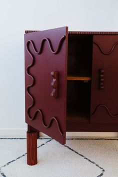 a wooden cabinet sitting on top of a carpeted floor next to a white wall