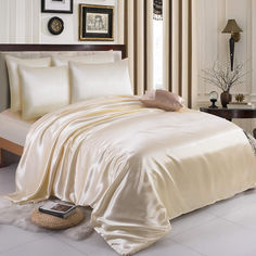 a bed with a white comforter and pillows on top of it in a room