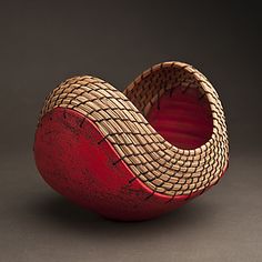 a red and brown basket sitting on top of a gray table next to a black wall