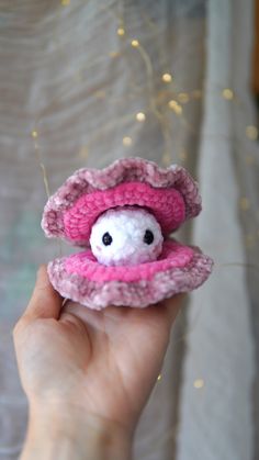 a hand holding a small stuffed animal in a pink hat