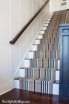 a stair case with black and white striped carpet on the bottom, next to a blue door