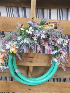 a wreath made out of green hoses with flowers on it sitting on top of a wooden pallet