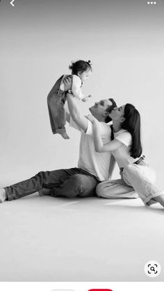 a man and woman sitting on the ground with a baby in their lap, holding an infant