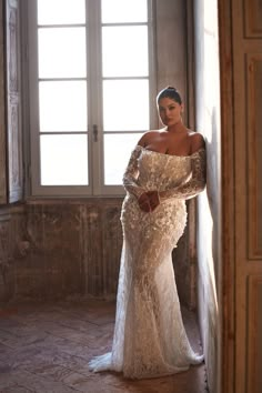 a woman in a white dress standing by a window