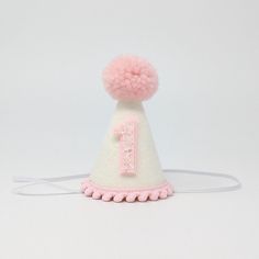 This Listing: Mini 3 inch hat with Pink pom and  trim & Pink glitter birthday number. Size:  Hat measures approximately 3 inches tall and 2 inches wide with an attached comfortable skinny elastic headband meant to be worn around the back of the head. (not under the chin) White Adjustable Mini Hats For Birthday, Adjustable White Mini Hat For Birthday, Adjustable Mini Hats With Round Crown For Birthdays, Adjustable White Mini Hat For Birthdays, Playful Adjustable Mini Hats For Birthday, Adjustable Mini Hats With Round Crown For Birthday, White Adjustable Mini Hat For Birthdays, Adjustable Pink Baseball Cap Birthday, Adjustable Round Crown Mini Hats For Birthday