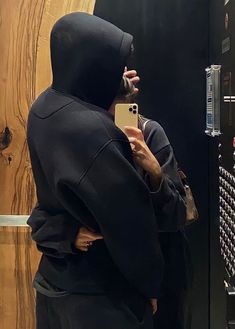 a person wearing a hoodie taking a selfie in front of a mirror