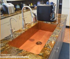 a copper sink in a kitchen with granite counter tops