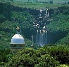 a large waterfall is in the distance with a dome on top