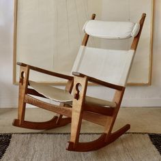 a wooden rocking chair in front of a painting