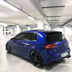 a blue car is parked in a parking garage with white walls and floors, while the back end of it's tail lights are visible