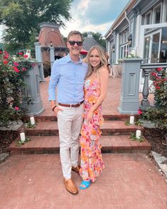 a man and woman posing for a photo in front of some flowers on the steps