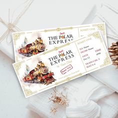 two tickets for the polar express sitting next to pine cones