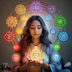 a woman sitting in front of seven chakras and holding her hands up to the light